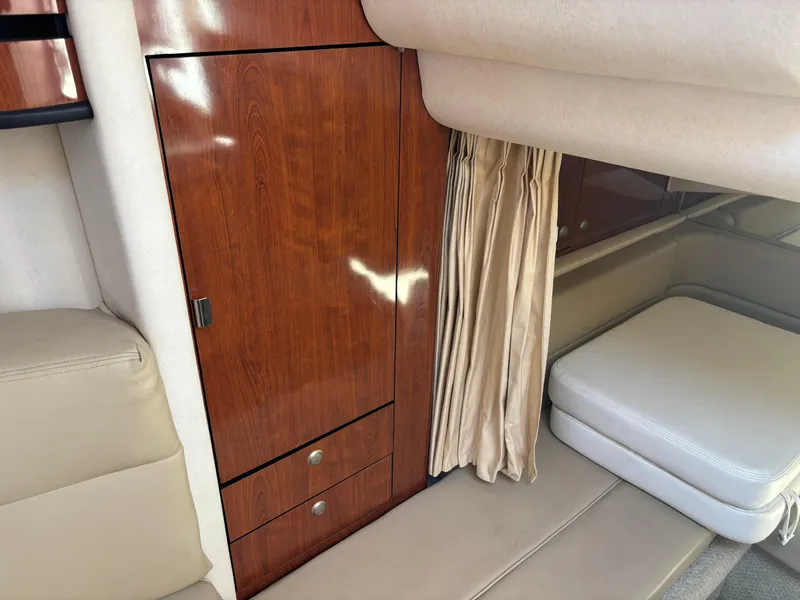 Slide: The Image of 2006 Sea Ray 300 Sundancer cabin interior with wood cabinetry and beige seating. - 12