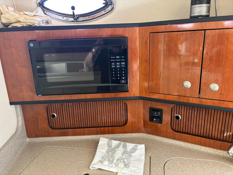 Slide: The Image of 2006 Sea Ray 300 Sundancer interior with microwave and wooden cabinetry. - 17
