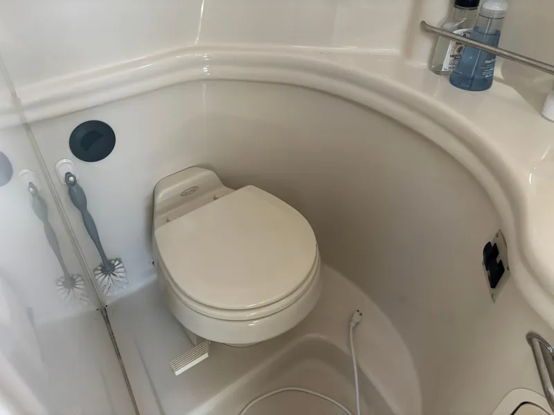 Slide: The Image of 2006 Sea Ray 300 Sundancer bathroom with toilet and cleaning supplies. - 20