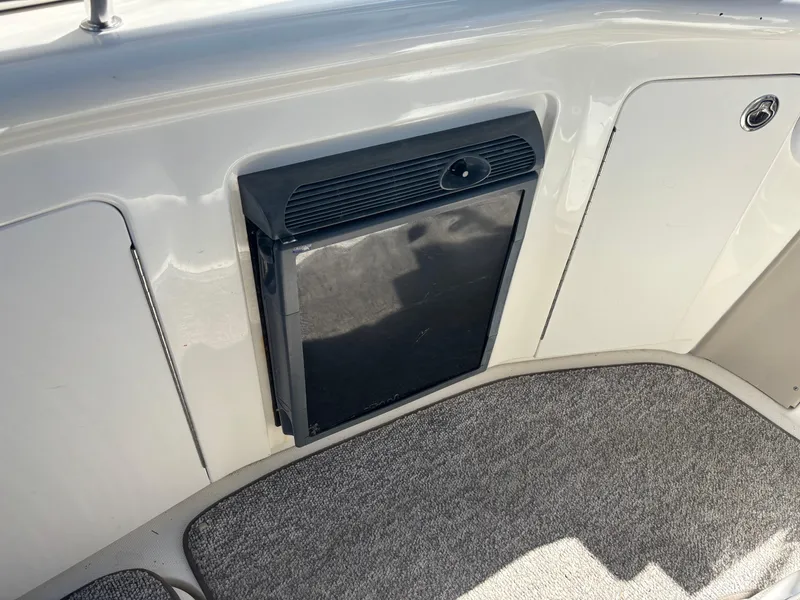 Slide: The Image of 2006 Sea Ray 300 Sundancer interior with built-in mini fridge and carpeted flooring. - 8