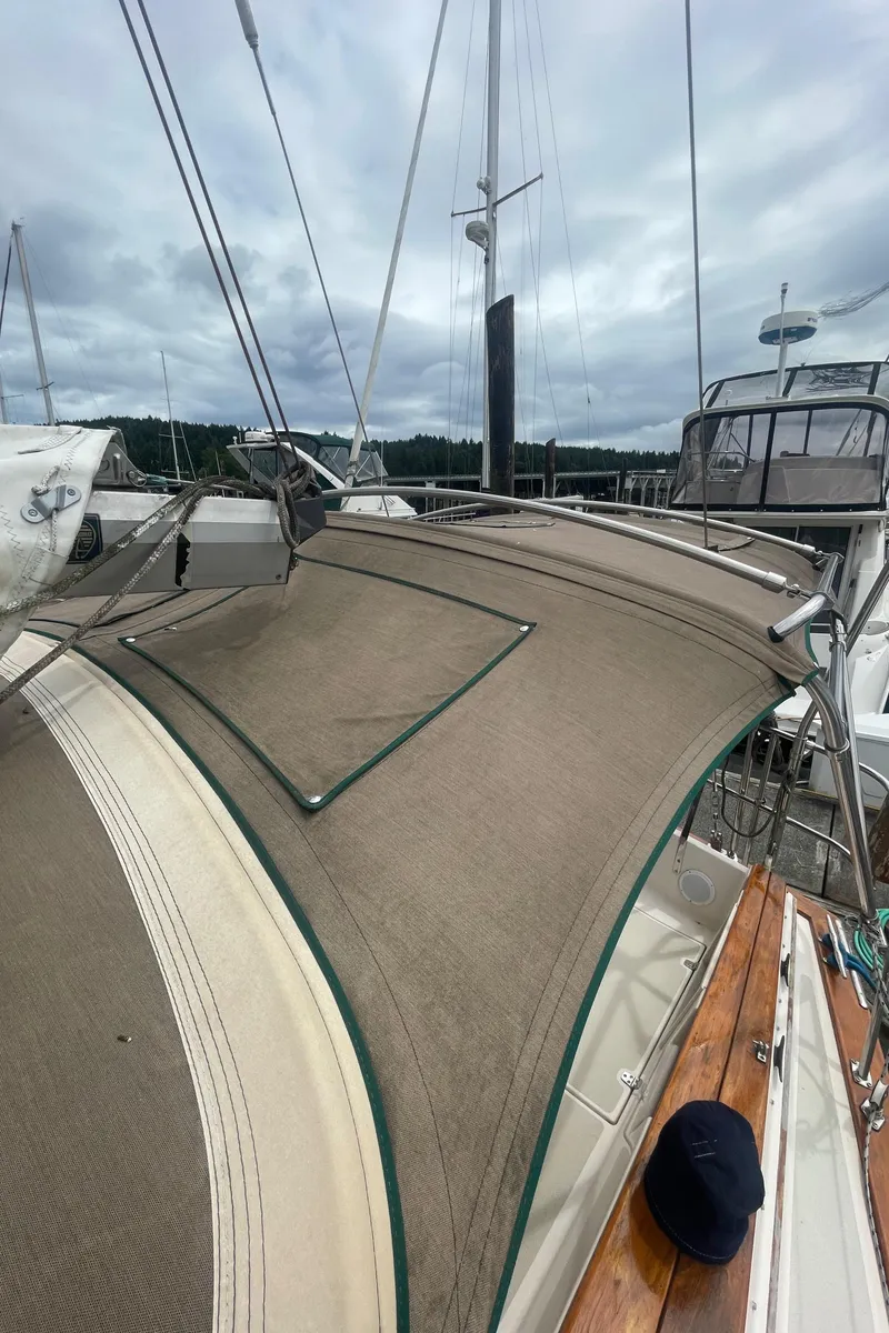 Slide: The Image of 1995 Island Packet 40 sailboat with beige canvas cover, docked under cloudy skies. - 15