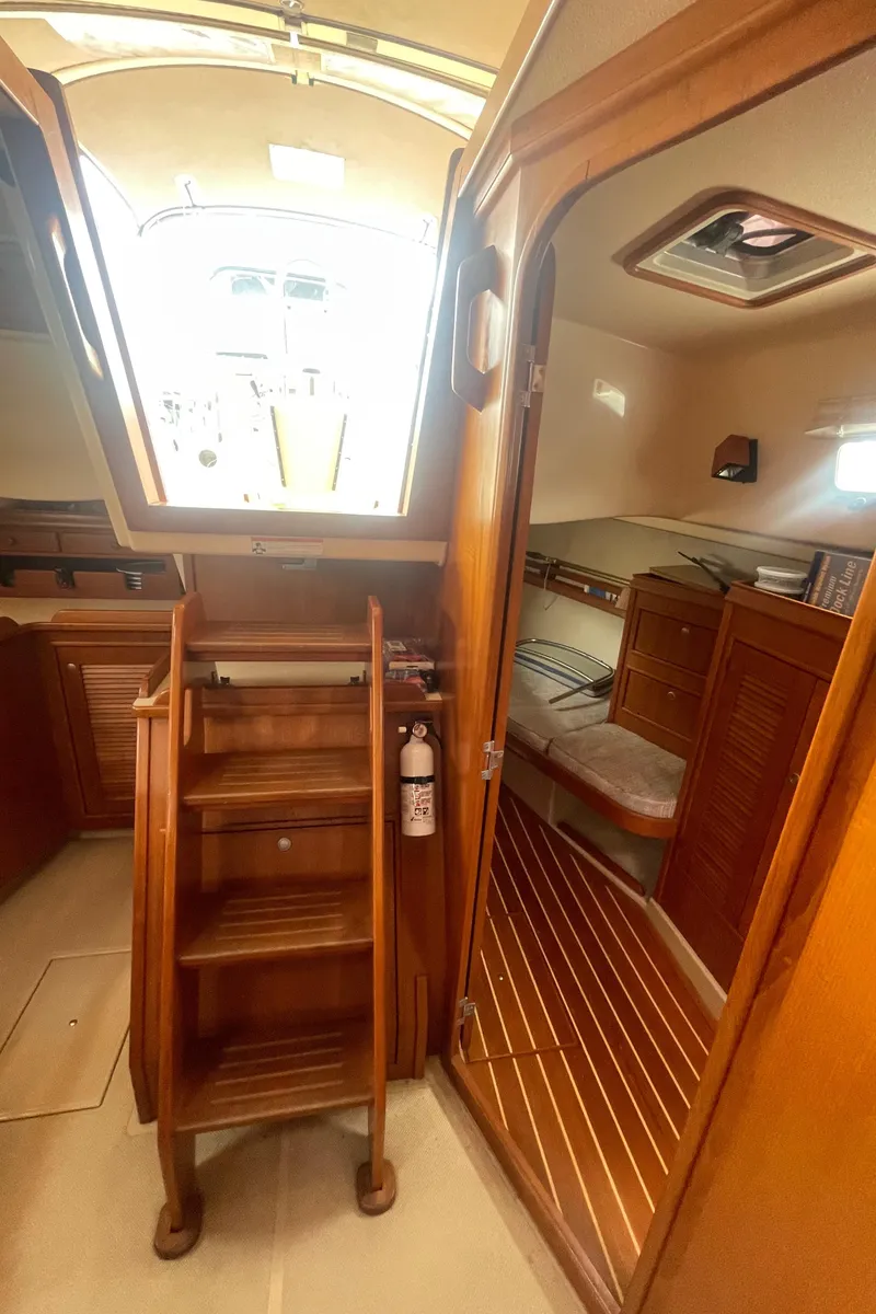 Slide: The Image of Interior of 1995 Island Packet 40 sailboat, featuring wooden stairs and cozy cabin space. - 21