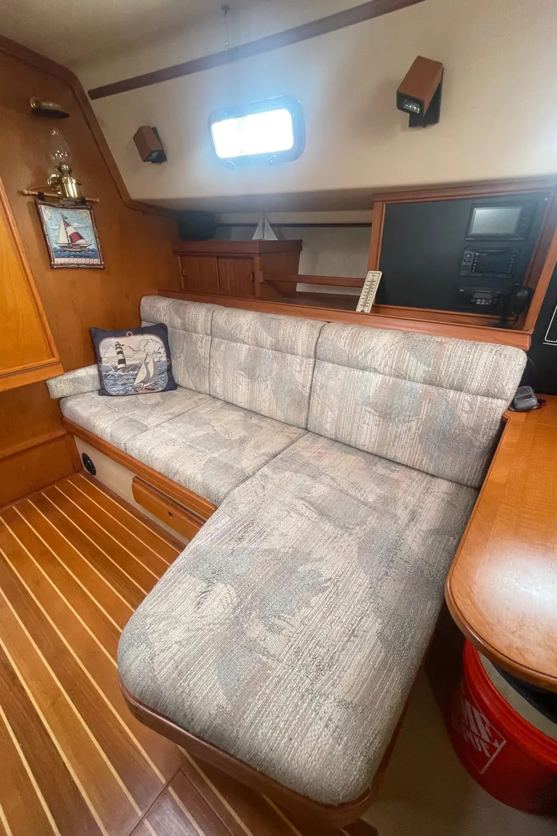 Slide: The Image of Interior of 1995 Island Packet 40 sailboat with cushioned seating and wooden accents. - 22