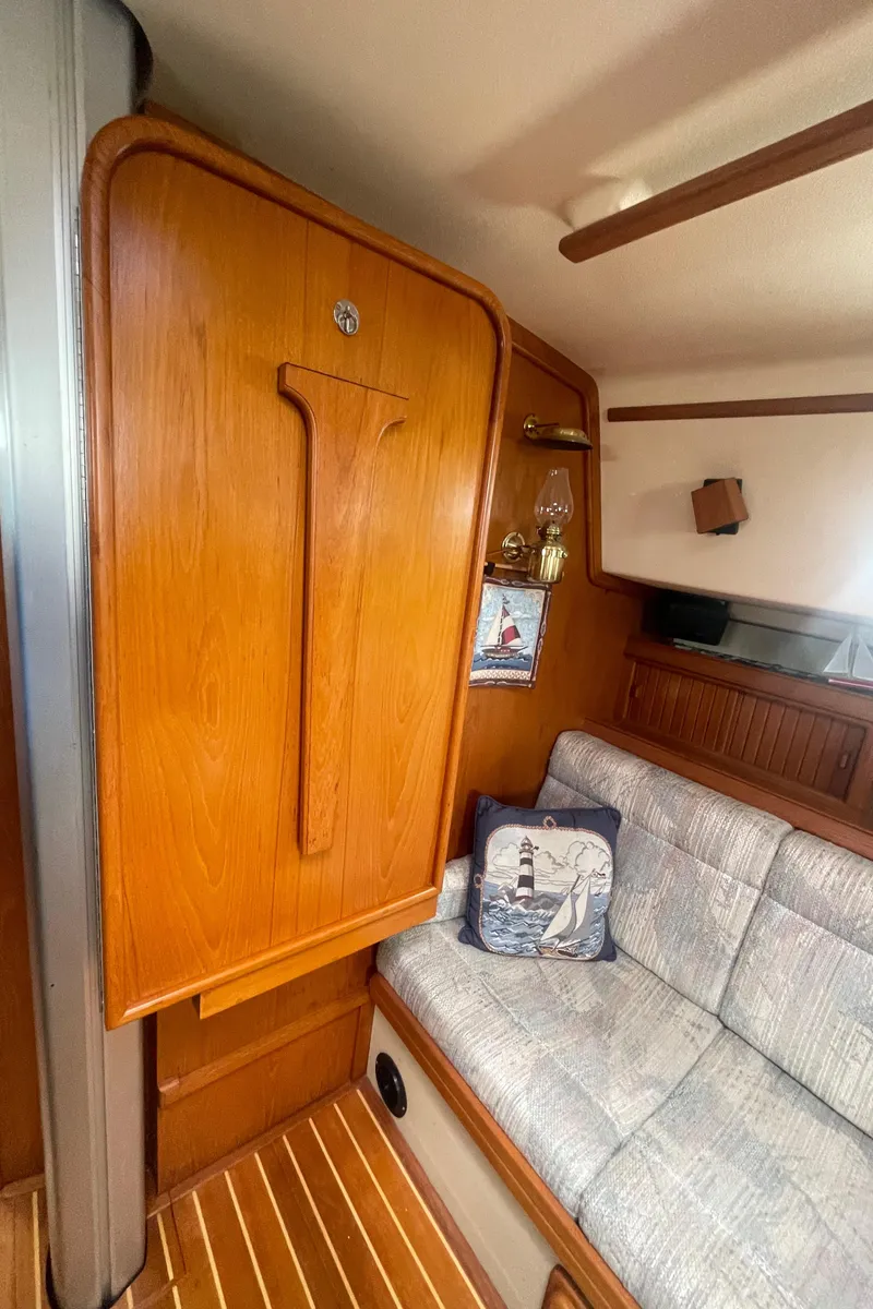 Slide: The Image of Interior of 1995 Island Packet 40 sailboat with wooden cabinetry and cushioned seating. - 25