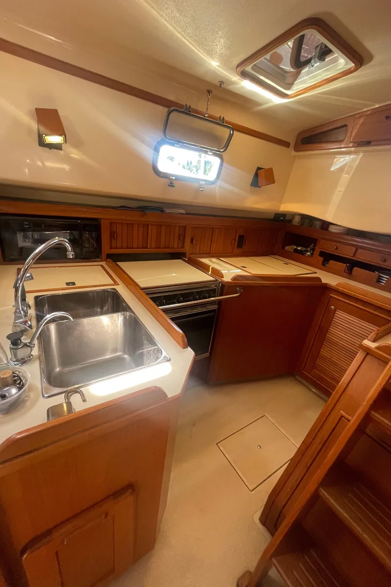 Slide: The Image of 1995 Island Packet 40 yacht kitchen with sink, stove, and wooden cabinetry. - 27