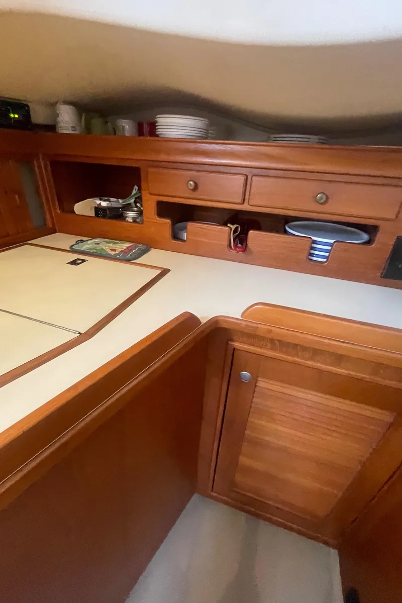 Slide: The Image of Interior of 1995 Island Packet 40 sailboat, featuring wooden cabinetry and organized storage. - 29