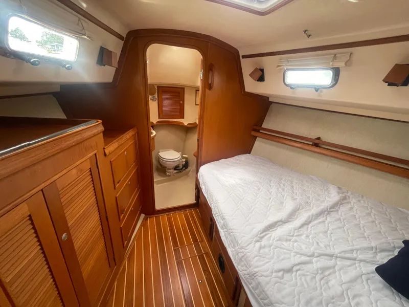 Slide: The Image of 1995 Island Packet 40 yacht interior with wooden cabinetry, bed, and bathroom. - 32