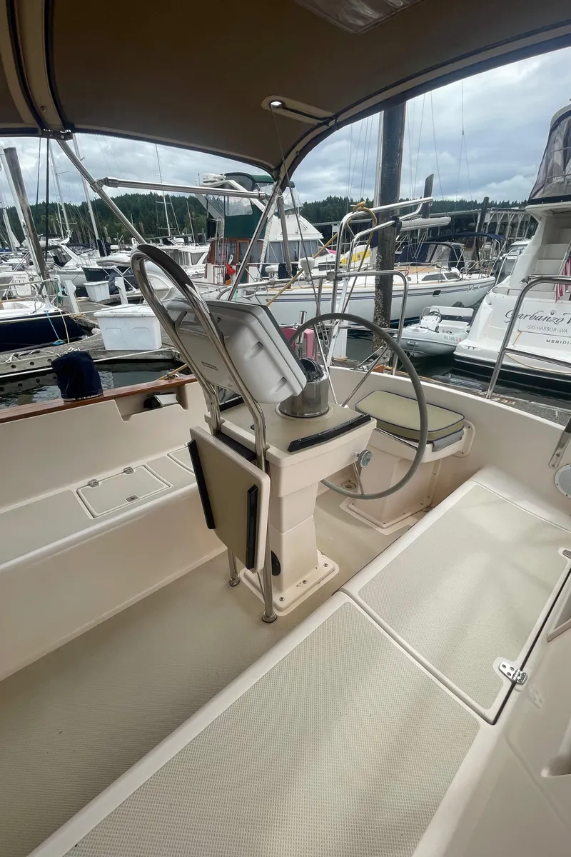 Slide: The Image of Cockpit of 1995 Island Packet 40 sailboat, featuring steering wheel and seating, docked at marina. - 4