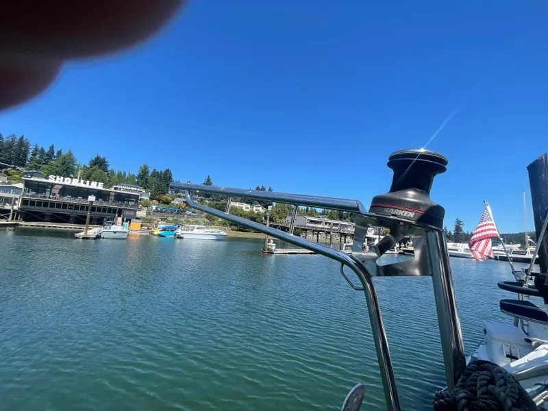 Slide: The Image of Island Packet 40 sailboat in marina, American flag, clear blue sky, shoreline buildings. - 48