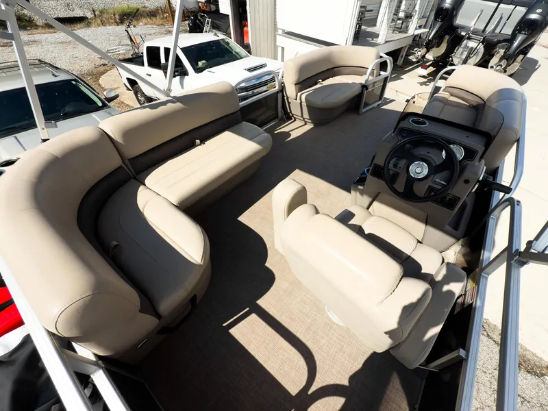 Slide: The Image of 2025 Sun Tracker Party Barge 16 DLX interior with beige seating and steering console. - 12