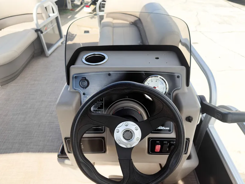 Slide: The Image of 2025 Sun Tracker Party Barge 16 DLX steering console with black wheel and dashboard controls. - 14