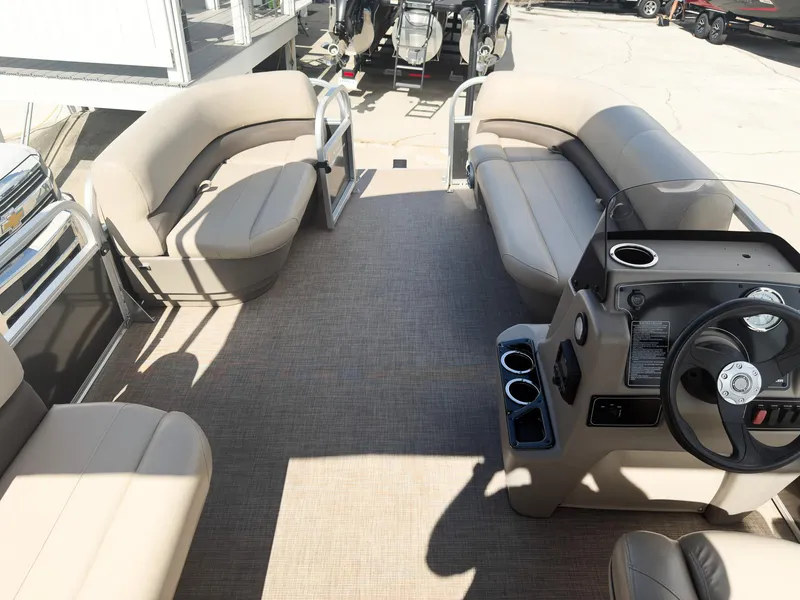 Slide: The Image of 2025 Sun Tracker Party Barge 16 DLX interior with beige seating and steering console. - 18