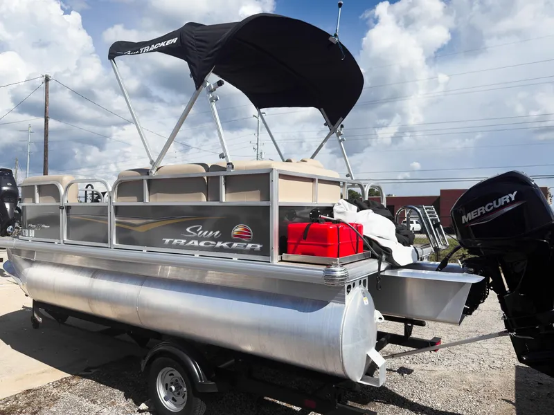 Slide: The Image of 2025 Sun Tracker Party Barge 16 DLX pontoon boat with Mercury engine, parked outdoors. - 20