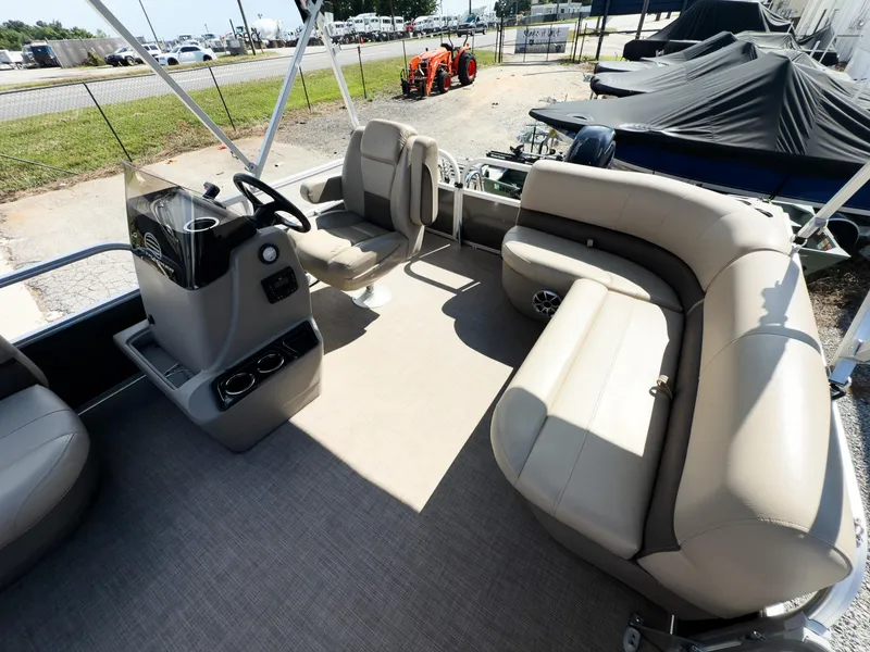 Slide: The Image of 2025 Sun Tracker Party Barge 16 DLX interior with beige seating and steering console. - 9