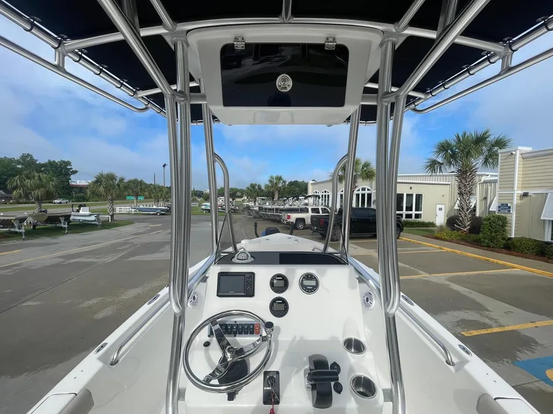 Slide: The Image of 2024 Key West 189 FS boat interior with steering console and canopy, parked outdoors. - 17