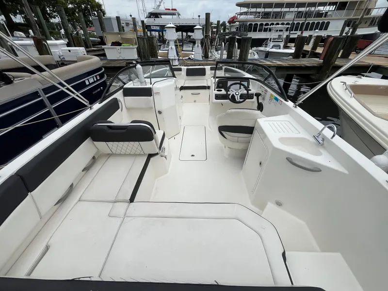 Slide: The Image of 2022 Bayliner DX 2200 boat interior with seating and steering wheel at marina. - 16
