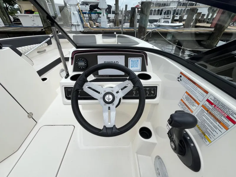 Slide: The Image of 2022 Bayliner DX 2200 boat dashboard with steering wheel and controls at marina. - 17