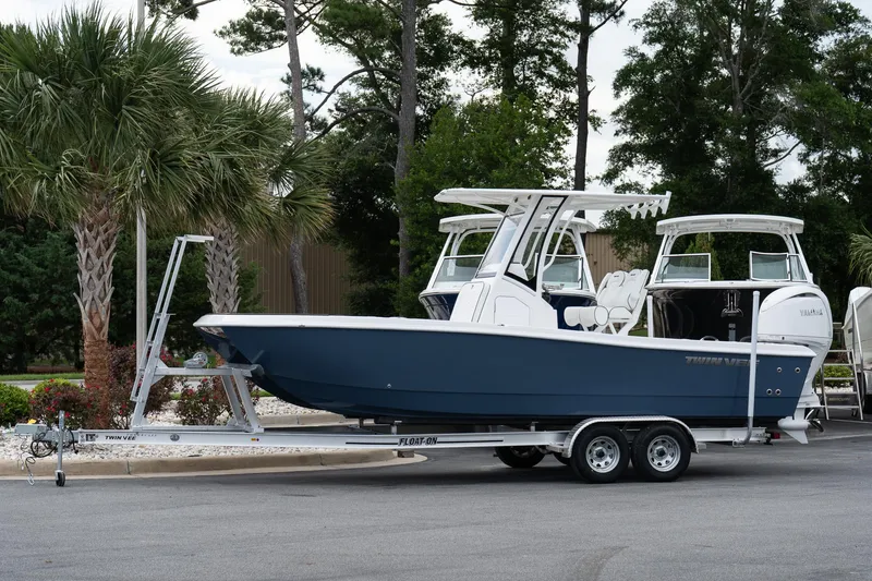 The Image of 2026 Twin Vee 22 Bay Cat boat on trailer, parked near palm trees. - 1
