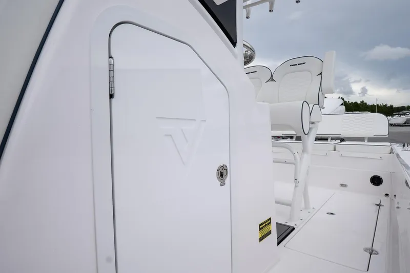 Slide: The Image of 2026 Twin Vee 22 Bay Cat boat interior with white seating and storage compartment. - 15