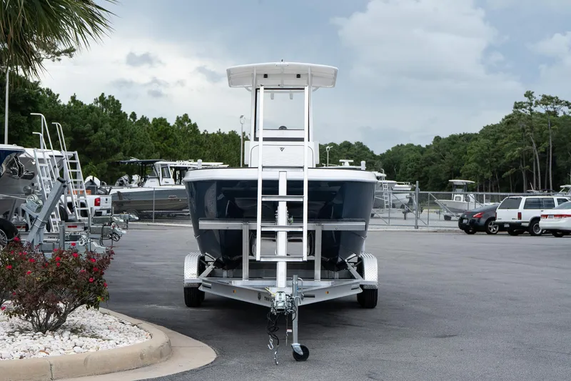 Slide: The Image of 2026 Twin Vee 22 Bay Cat boat on trailer in parking lot, surrounded by trees and vehicles. - 3