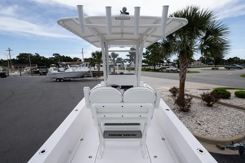 Slide: The Image of 2026 Twin Vee 22 Bay Cat boat with T-top, parked near palm trees. - 8
