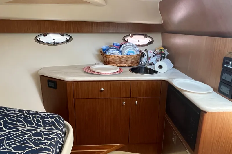 Slide: The Image of 2015 Tiara Yachts 3100 Coronet interior with kitchenette, featuring wood cabinetry and countertop. - 11