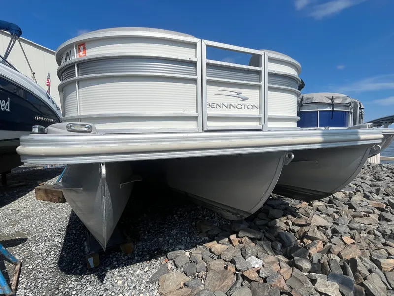 Slide: The Image of 2021 Bennington 23L pontoon boat on rocky shore under clear blue sky. - 11