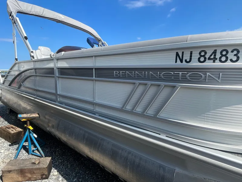 Slide: The Image of 2021 Bennington 23L pontoon boat on stands, clear sky background. - 12