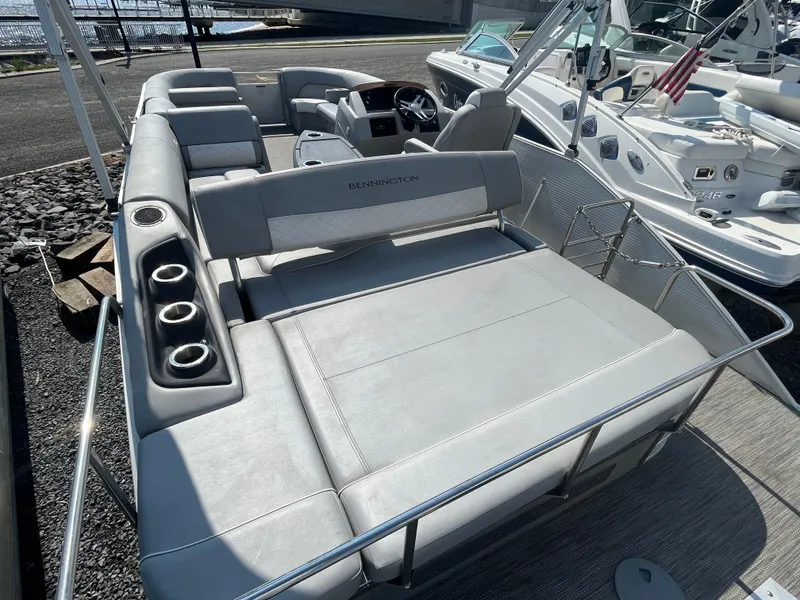 Slide: The Image of 2021 Bennington 23L pontoon boat with spacious seating and cup holders, docked near water. - 23