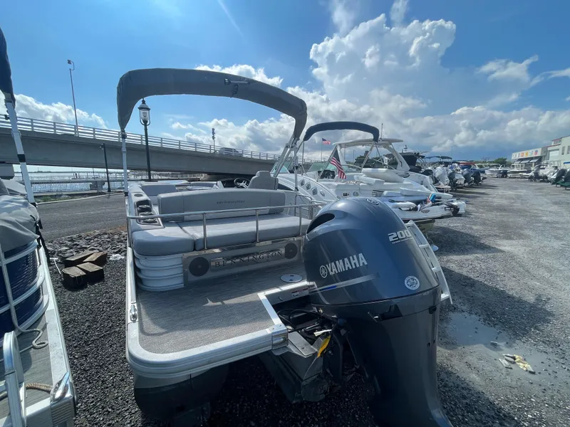 Slide: The Image of 2021 Bennington 23L pontoon boat with Yamaha 200 engine, parked near a bridge. - 8