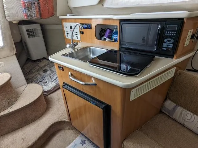 Slide: The Image of 2002 Bayliner 245 Ciera interior kitchen with sink, microwave, and compact fridge. - 12