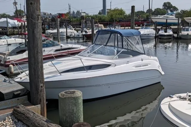Slide: The Image of 2002 Bayliner 245 Ciera boat docked in a marina, surrounded by other vessels. - 3