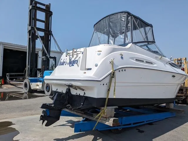 Slide: The Image of 2002 Bayliner 245 Ciera boat on a blue trailer, docked near a forklift. - 4