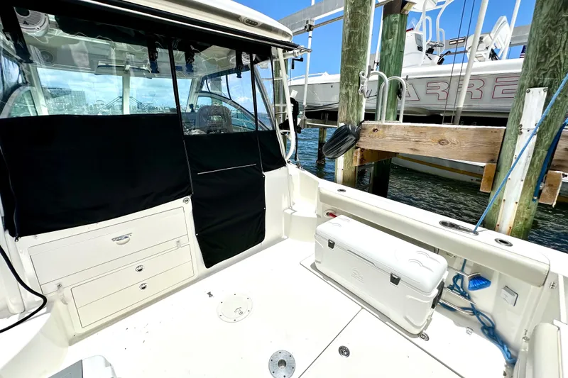 Slide: The Image of 2015 Boston Whaler 315 Conquest boat interior at dock, featuring storage and seating. - 14