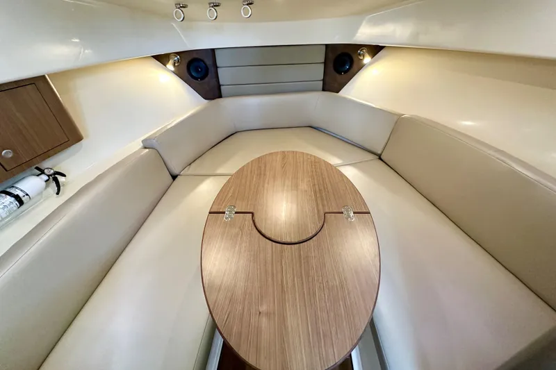 Slide: The Image of Interior of 2015 Boston Whaler 315 Conquest, featuring a cozy seating area and wooden table. - 28