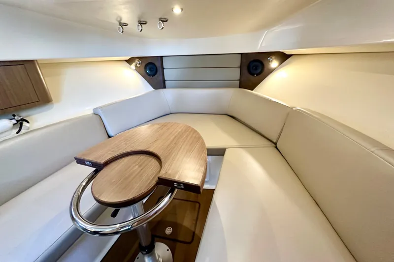 Slide: The Image of 2015 Boston Whaler 315 Conquest cabin with beige seating and wooden table. - 30