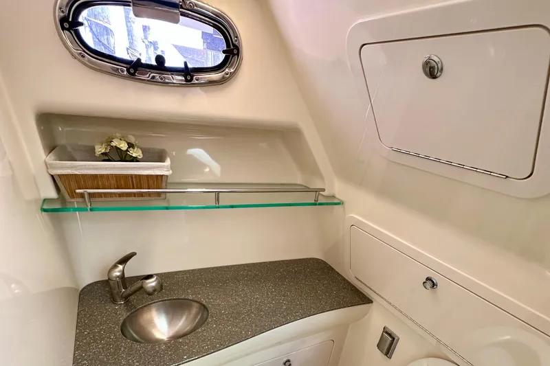 Slide: The Image of 2015 Boston Whaler 315 Conquest bathroom with sink, porthole, and storage compartments. - 33