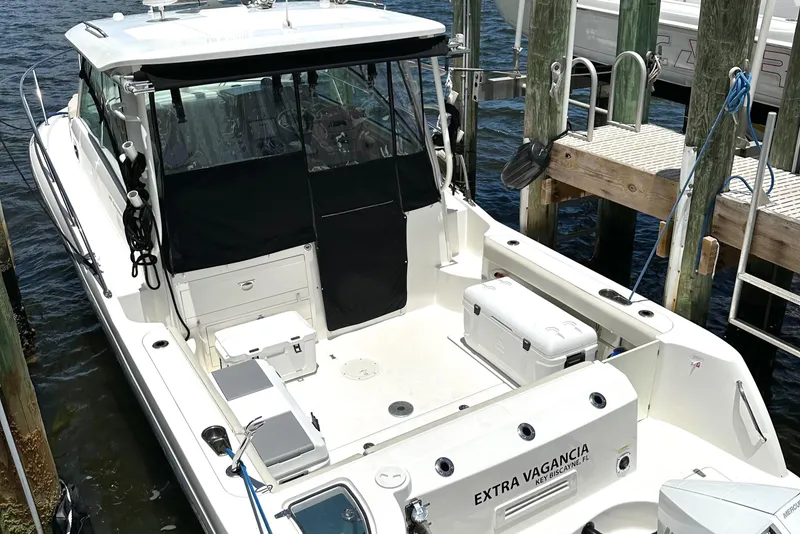 Slide: The Image of 2015 Boston Whaler 315 Conquest docked, featuring spacious deck and seating area. - 5