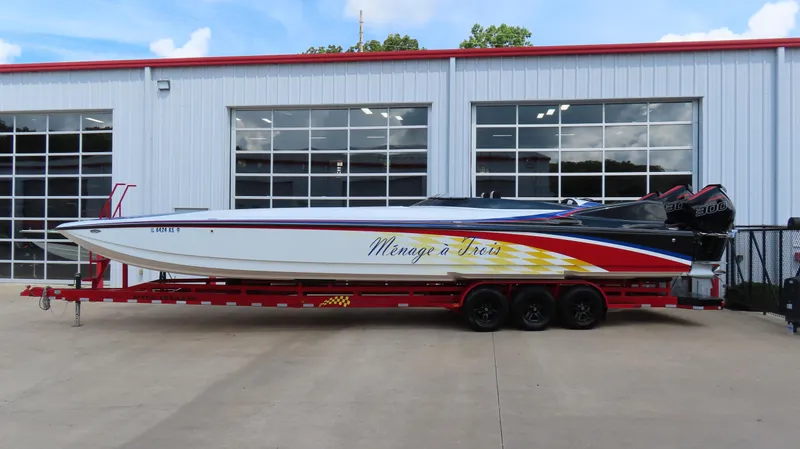 Slide: The Image of 1995 Talon 36 Cat powerboat on red trailer, parked outside a garage. - 22