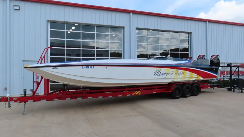 Slide: The Image of 1995 Talon 36 Cat boat on red trailer, parked outside a garage. - 23