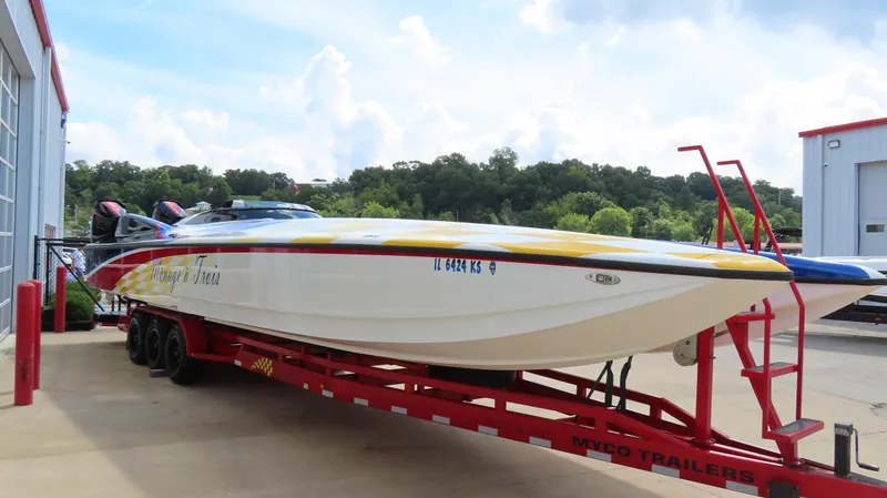 Slide: The Image of 1995 Talon 36 Cat powerboat on red trailer, parked near a building, with scenic background. - 6