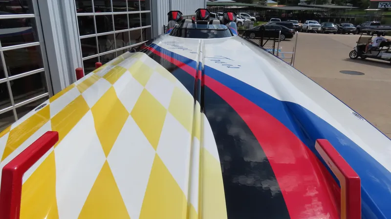 Slide: The Image of 1995 Talon 36 Cat boat with vibrant yellow, red, and blue racing stripes. - 7