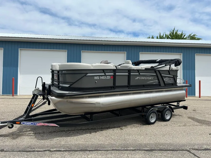 Slide: The Image of 2022 Starcraft CX21 pontoon boat on trailer, parked outside blue storage facility. - 12