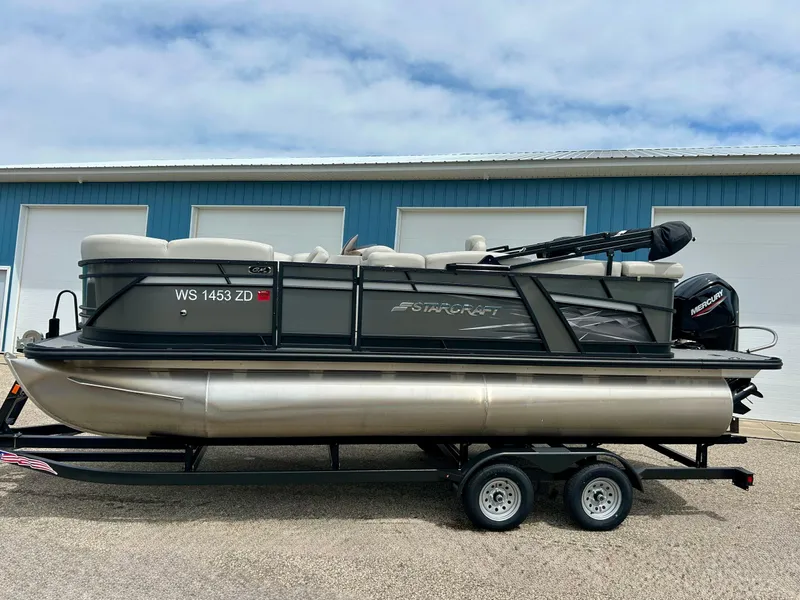 Slide: The Image of 2022 Starcraft CX21 pontoon boat on trailer, parked outside blue storage units. - 13