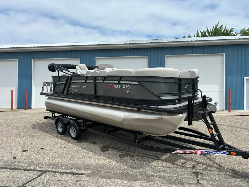Slide: The Image of 2022 Starcraft CX21 boat dashboard with steering wheel, gauges, and lake view. - 2