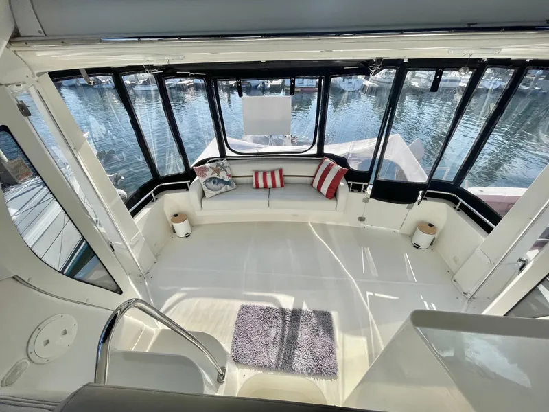 Slide: The Image of 2004 Carver 44 Cockpit Motor Yacht interior with seating, cushions, and marina view. - 10