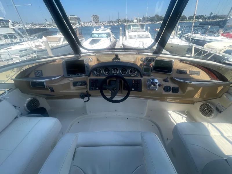 Slide: The Image of 2004 Carver 44 Cockpit Motor Yacht helm with navigation instruments and marina view. - 16
