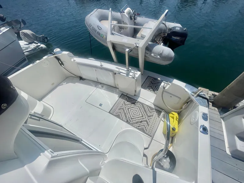 Slide: The Image of 2004 Carver 44 Cockpit Motor Yacht with dinghy, docked, featuring spacious deck and patterned rug. - 3