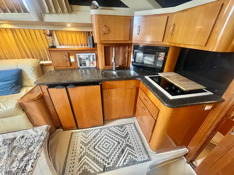 Slide: The Image of 2004 Carver 44 Cockpit Motor Yacht kitchen with wood cabinets and modern appliances. - 53