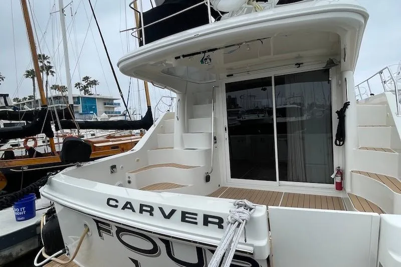 Slide: The Image of 2006 Carver 42 Super Sport yacht docked, featuring spacious deck and sliding glass doors. - 10